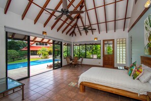 Ein Schlafzimmer mit einem großen Bett, einem Deckenventilator und Blick auf einen Swimmingpool.