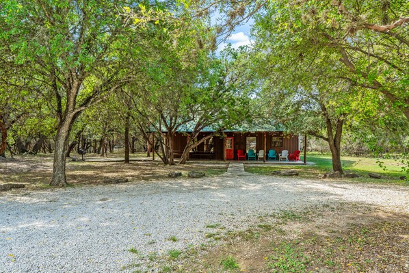 A rustic cabin with a gravel path leading to it, surrounded by trees. - Steps from THE Frio River with river access included, the perfect Concan cottage with the best price (Concan)