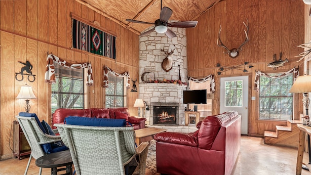 A cozy cabin interior with a stone fireplace, leather furniture, and antler decorations. - Steps from THE Frio River with river access included, the perfect Concan cottage with the best price (Concan)