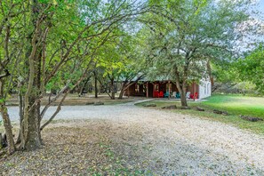 A rustic cabin with a gravel path leading to it, surrounded by trees and a small pond. - Steps from THE Frio River with river access included, the perfect Concan cottage with the best price (Concan)