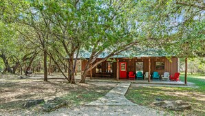 A cabin with a covered porch, outdoor seating, and a gravel path leading to the entrance. - Steps from THE Frio River with river access included, the perfect Concan cottage with the best price (Concan)