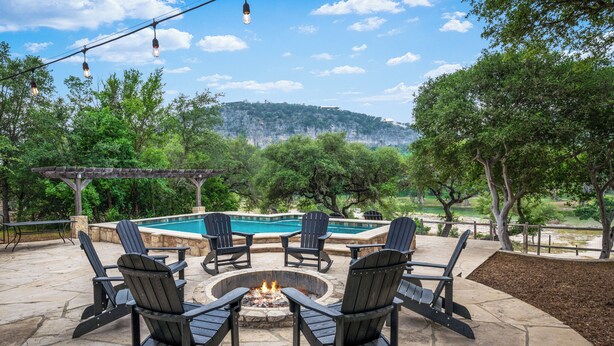An outdoor patio with Adirondack chairs, a fire pit, and a swimming pool. - Directly ON THE Frio river, with a private pool and room for up to 37! (Concan)
