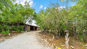 A gravel path leading to a wooden cabin surrounded by trees. - Cottage in the heart of Concan surrounded by nature & less than 5-minute drive to THE Frio River (Concan)
