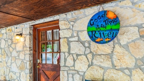 A stone wall with a wooden door and a circular sign that reads "Good Time at the River." - Cottage in the heart of Concan surrounded by nature & less than 5-minute drive to THE Frio River (Concan)
