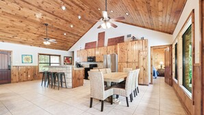 Una cocina amplia con armarios de madera, una isla central y un comedor con sillas.