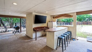 Een keukenhoek met een bar, een aan de muur bevestigde televisie en een bordje met de tekst 'TINTUS TAVERN'.