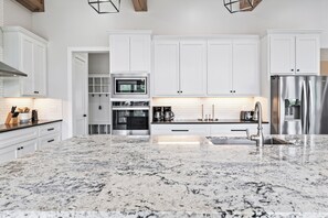 A modern kitchen with white cabinetry, stainless steel appliances, and a granite countertop.