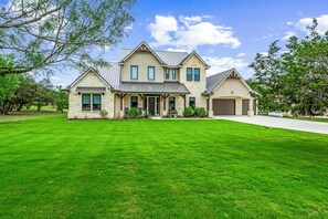 A two-story house with a stone facade, a front porch, and a well-maintained lawn.