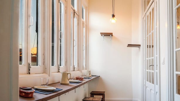 Un couloir étroit avec un comptoir en bois, de nombreuses fenêtres et un luminaire suspendu.