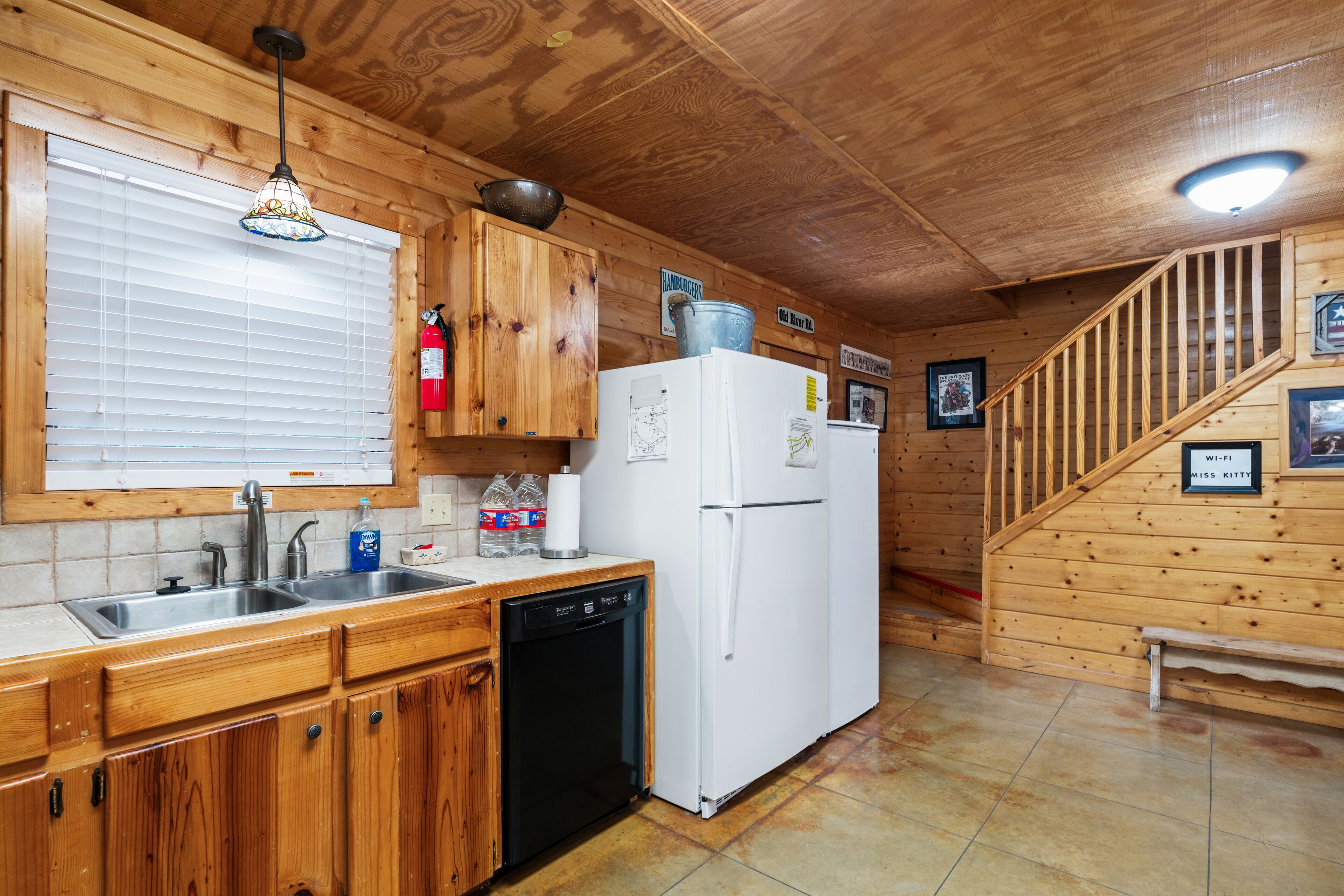 A wooden cabin kitchen with a sink, dishwasher, and refrigerator.