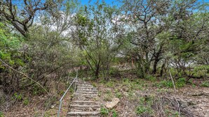 Un escalier en pierre menant au sommet d’une colline, entouré d’arbres et d’arbustes denses.