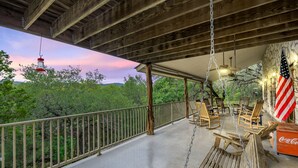 Un espace extérieur abrité, aménagé avec du mobilier en bois, un drapeau américain et un réfrigérateur contenant des boissons Coca-Cola.