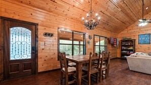 A wooden interior with a dining table and chairs, a sofa, and a chandelier. - Right in the heart of Concan, private swimming pool, epic views & a 2-minute drive to THE Frio River (Concan)