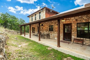 A stone building with a covered patio, outdoor seating, and satellite dishes.