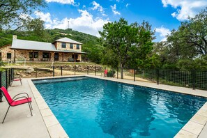 A swimming pool with a stone house in the background.