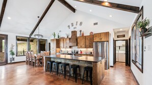 A spacious kitchen with a central island, wooden cabinets, and a stainless steel refrigerator. - Private pool, volleyball, basketball, outdoor fireplace & less than 5-minute drive to THE Frio River (Concan)