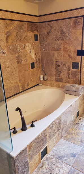Ein Badezimmer mit freistehender Badewanne, Steinwänden und einer Duschkabine aus Glas.