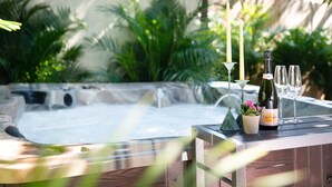 A hot tub with a candle and a bottle of wine on a wooden deck surrounded by greenery. - Luxury Home - Jacuzzi! Mini-Golf! Ping-Pong! Pets! 2 Desks! Yoga! Beach Gear! (North Palm Beach)
