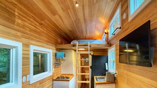 Une petite cabine équipée d’un coin cuisine, d’un canapé, d’une échelle menant au lit supérieur et d’un extincteur.
