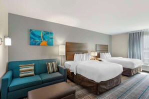 A hotel room with two beds, a sofa, a painting, and a large window with curtains. - MainStay Suites North - Central York (York)