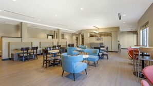A spacious indoor area with multiple seating arrangements including tables and chairs, a reception desk, and a counter. - MainStay Suites North - Central York (York)
