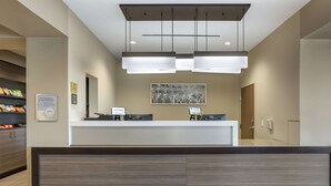 A reception area with a modern desk, two computer monitors, and a hanging light fixture. - MainStay Suites North - Central York (York)
