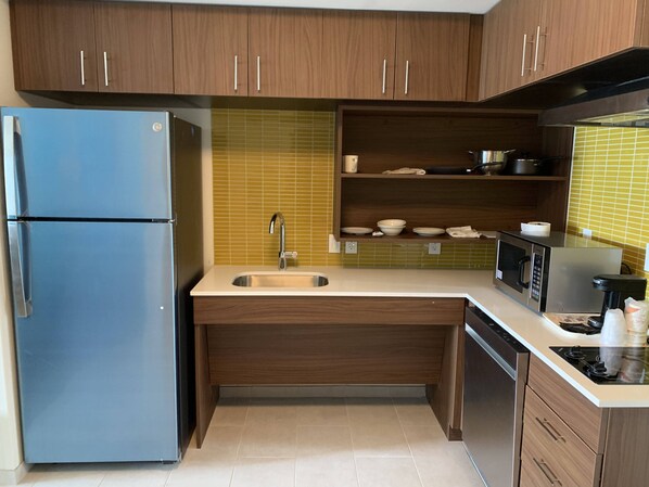 A compact kitchen with wooden cabinets, a built-in sink, a microwave, and a stove. - MainStay Suites North - Central York (York)