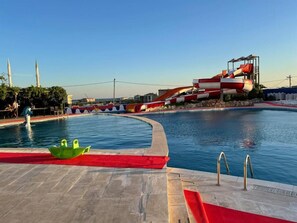 Une piscine avec un toboggan et un bateau vert.