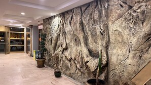 A lobby with a rock wall, potted plants, and a car entrance. - Respiro Park Hotel (Istanbul)