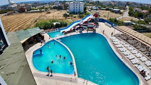 A swimming pool with a water slide, sun loungers, and a view of the surrounding area. - Respiro Park Hotel (Istanbul)