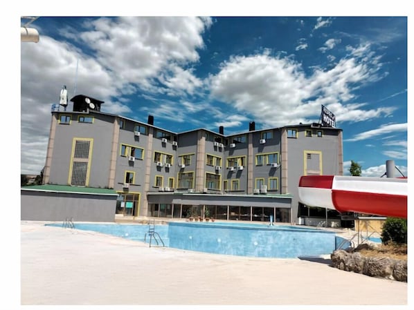Un hôtel avec plusieurs étages, des balcons et une piscine.