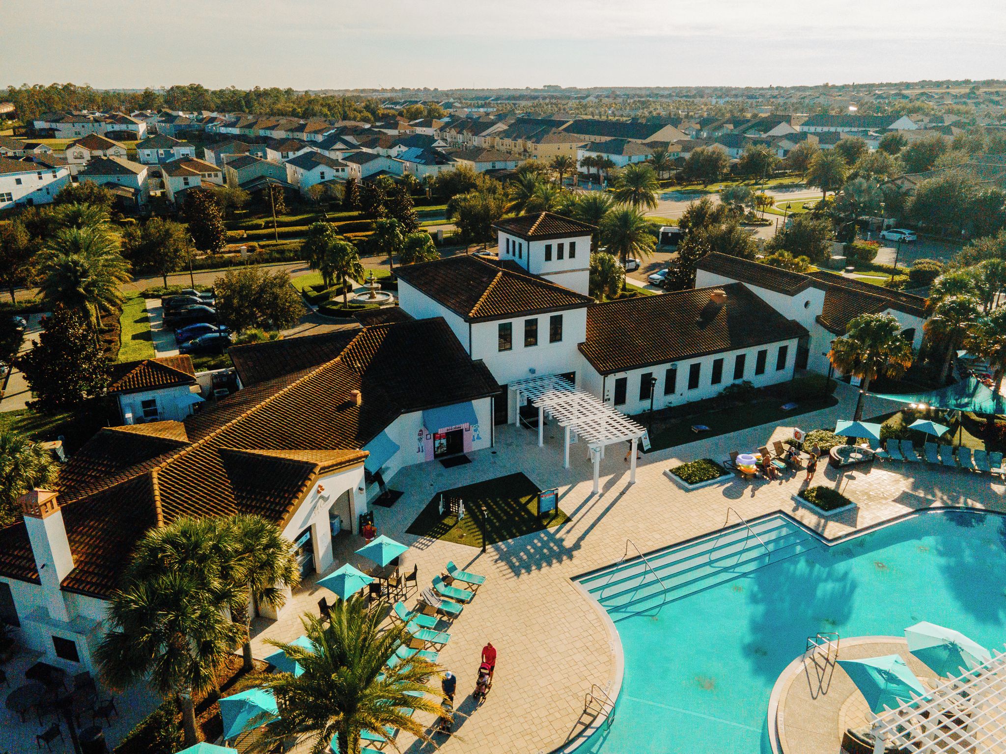 An aerial view of a resort with a swimming pool, lounge chairs, and a pavilion.