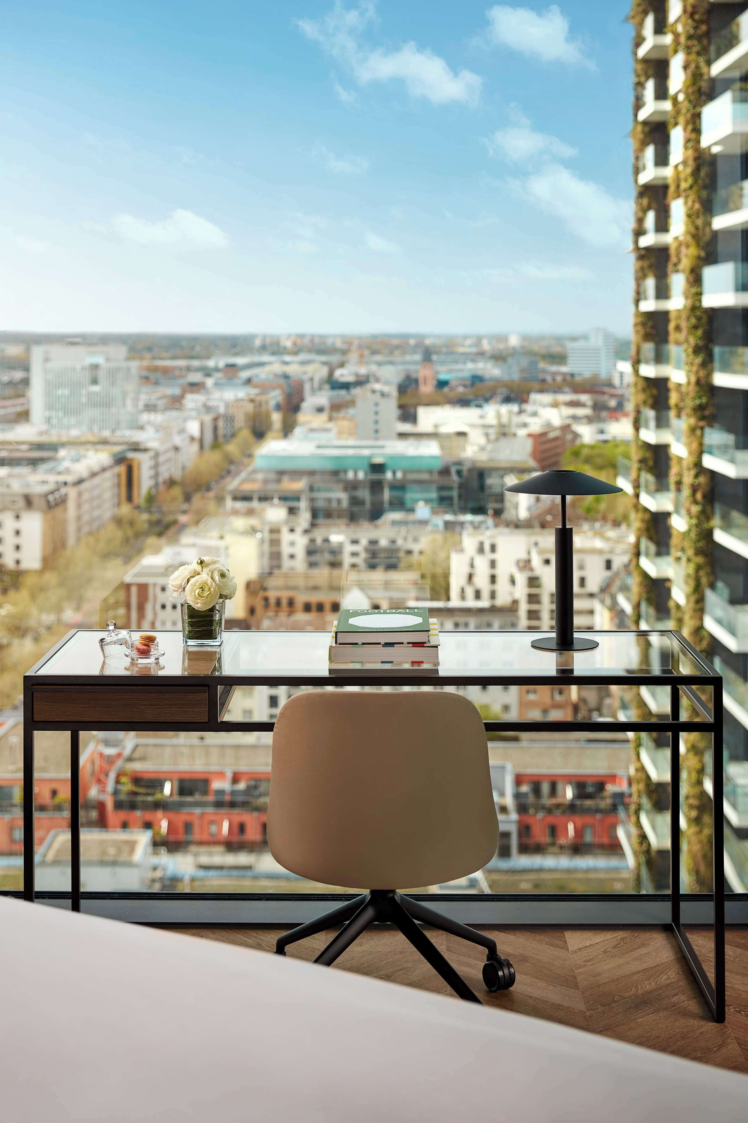 Un espace de bureau moderne comprenant un bureau, une chaise et une vue sur le paysage urbain, grâce à de grandes fenêtres.