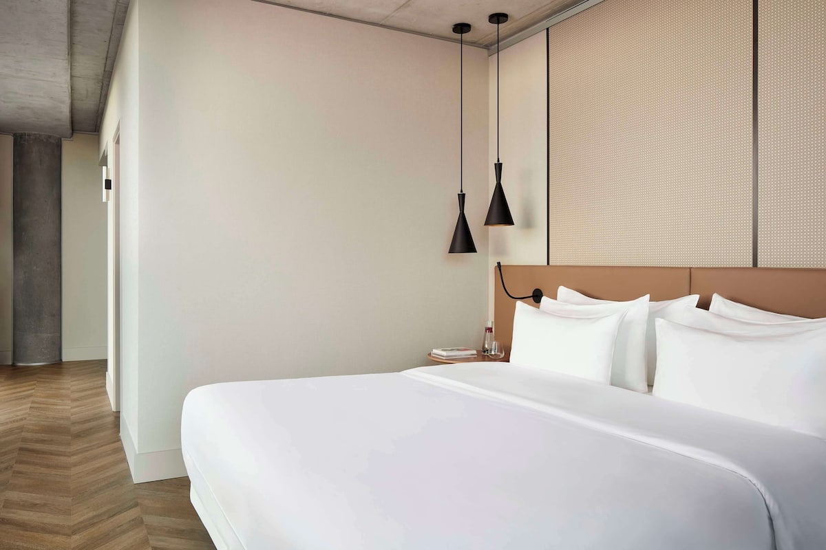 Een moderne hotelkamer met een groot bed, een houten vloer en een groot raam.