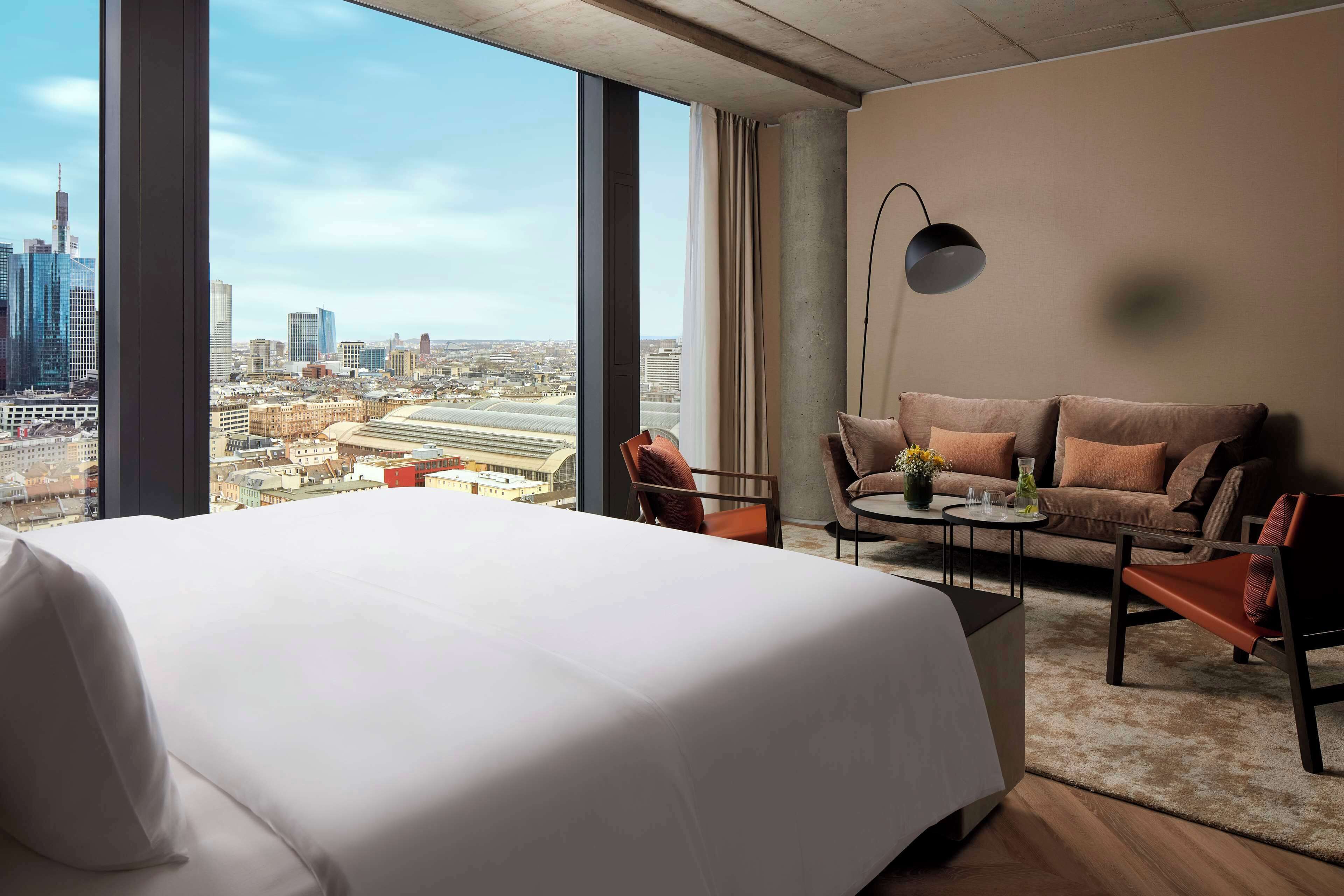 Une chambre d’hôtel avec un grand lit, un canapé, une petite table et une vue sur le paysage urbain.