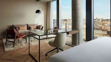 Ein modernes Hotelzimmer mit großem Fenster, Schreibtisch, Stuhl, Sofa und Bett.