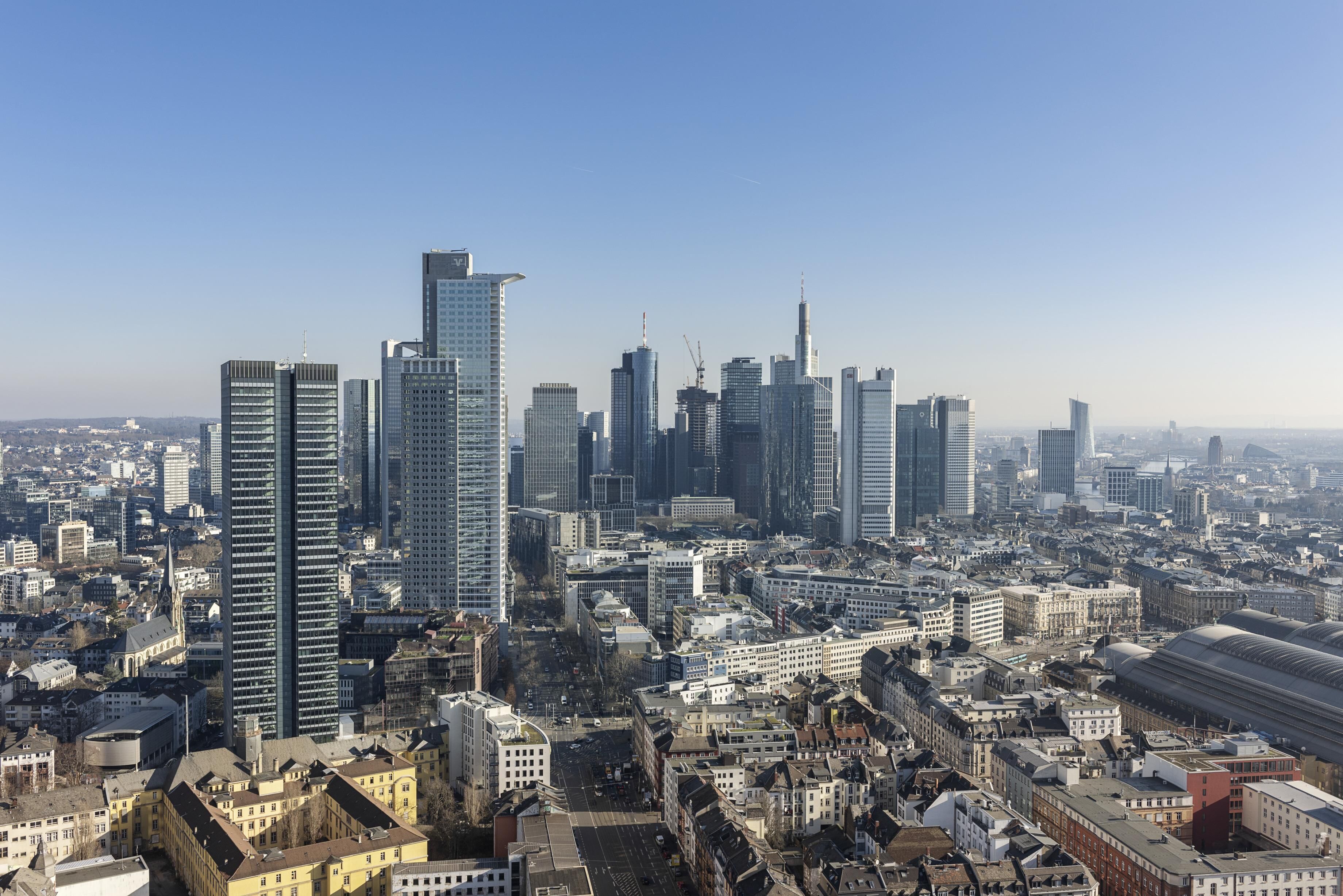 A cityscape with modern high-rise buildings, a mix of commercial and residential structures, and a prominent train station.