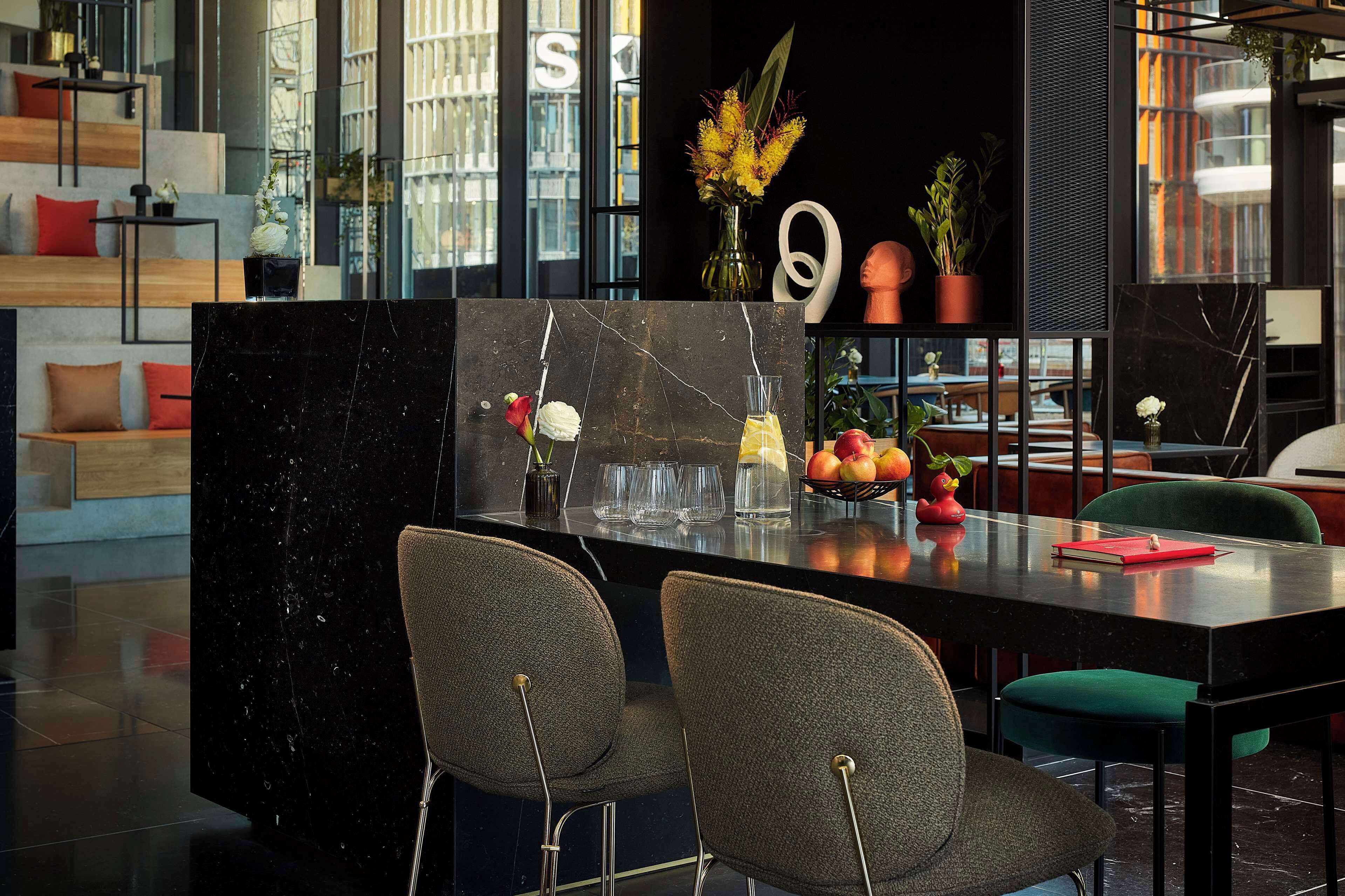 A modern kitchen with a marble island, two grey chairs, and a red notebook on the counter.