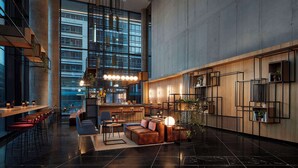 A spacious lobby with a bar area, seating, and a large window offering a view of the city.