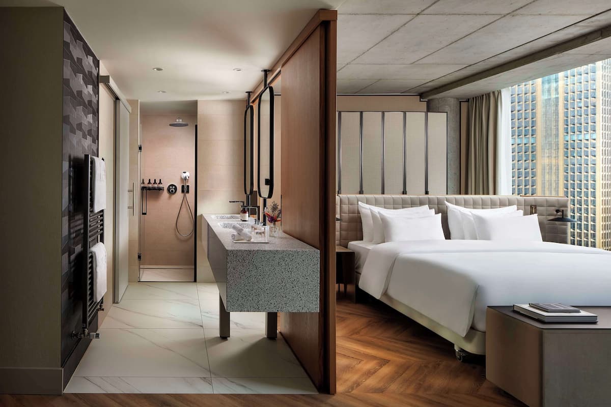 Een moderne hotelkamer met een groot bed, een bureau en uitzicht op een stadsgezicht.