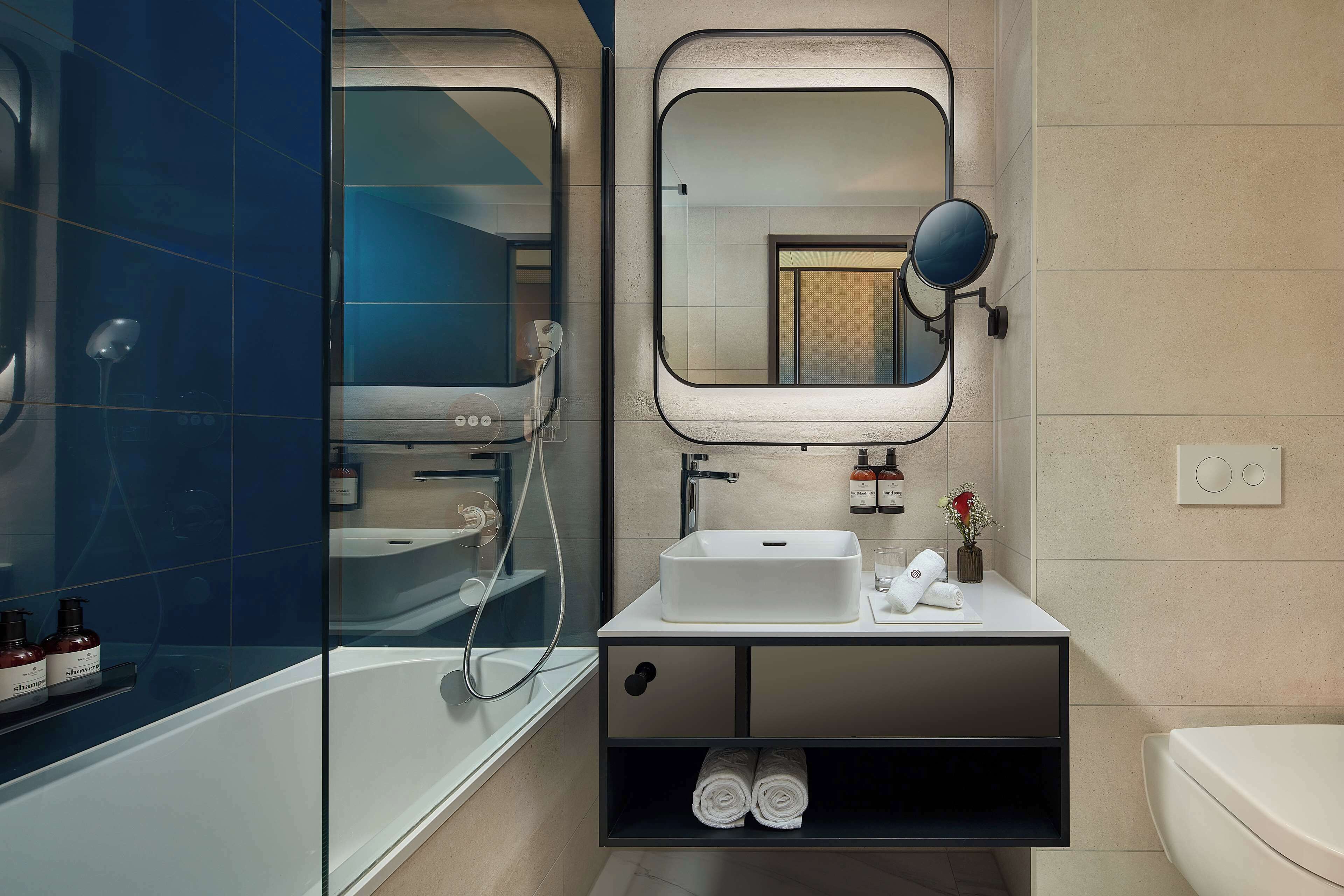 A modern bathroom with a glass-enclosed shower, a white sink, and a mirror with a round frame.