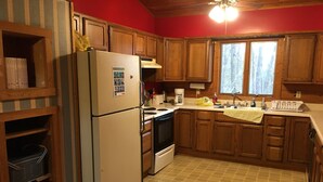 A kitchen with wooden cabinets, a refrigerator, a stove, and a window.