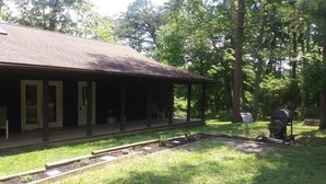 A covered outdoor area with a picnic table and a barbecue grill.
