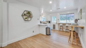A modern kitchen with white cabinets, a wooden countertop, and a hexagonal wall art piece.