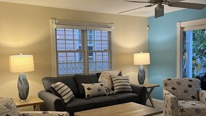 Ein Wohnzimmer mit einer Couch, zwei Sesseln, einem Couchtisch und einem Deckenventilator.