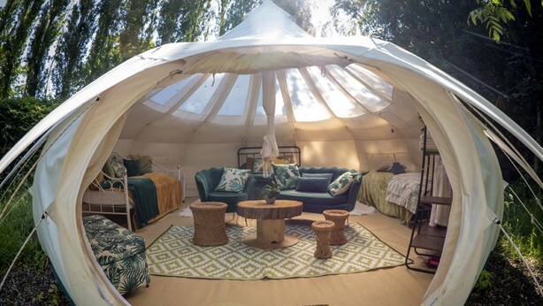 A spacious tent with a high ceiling, a cozy seating area with a sofa and armchairs, and a small table. - Orion 4-person Stunning Lotus Belle Tent (Ross-on-Wye)