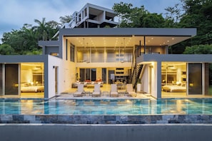 Ein modernes, zweistöckiges Haus mit Swimmingpool, Essbereich und Küche.