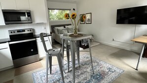 Een moderne keuken met een magnetron, oven en een eethoek met een tafel en stoelen.