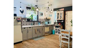 A kitchen with a wooden floor, a white chair, and a cabinet with a sign that says "Eat". - Cozy, 1 bedroom Cottage with Mountain views! (Tolleson)