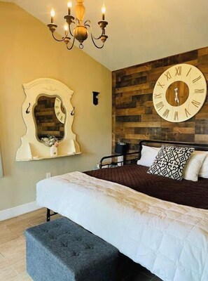 Cozy retreat with a large bed, round wall clock, and modern chandelier.